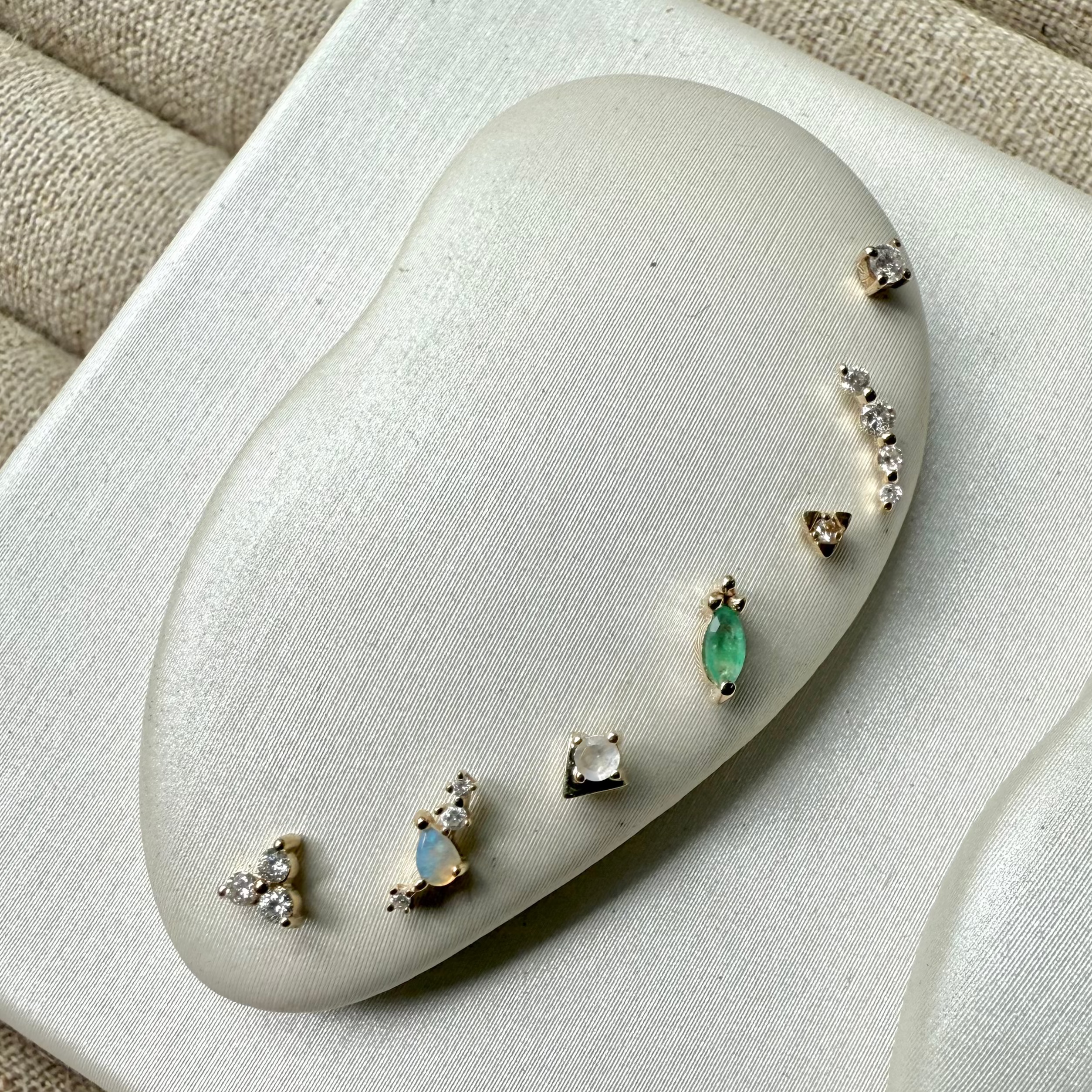 Set of earrings on a white cushion with a beige fabric background