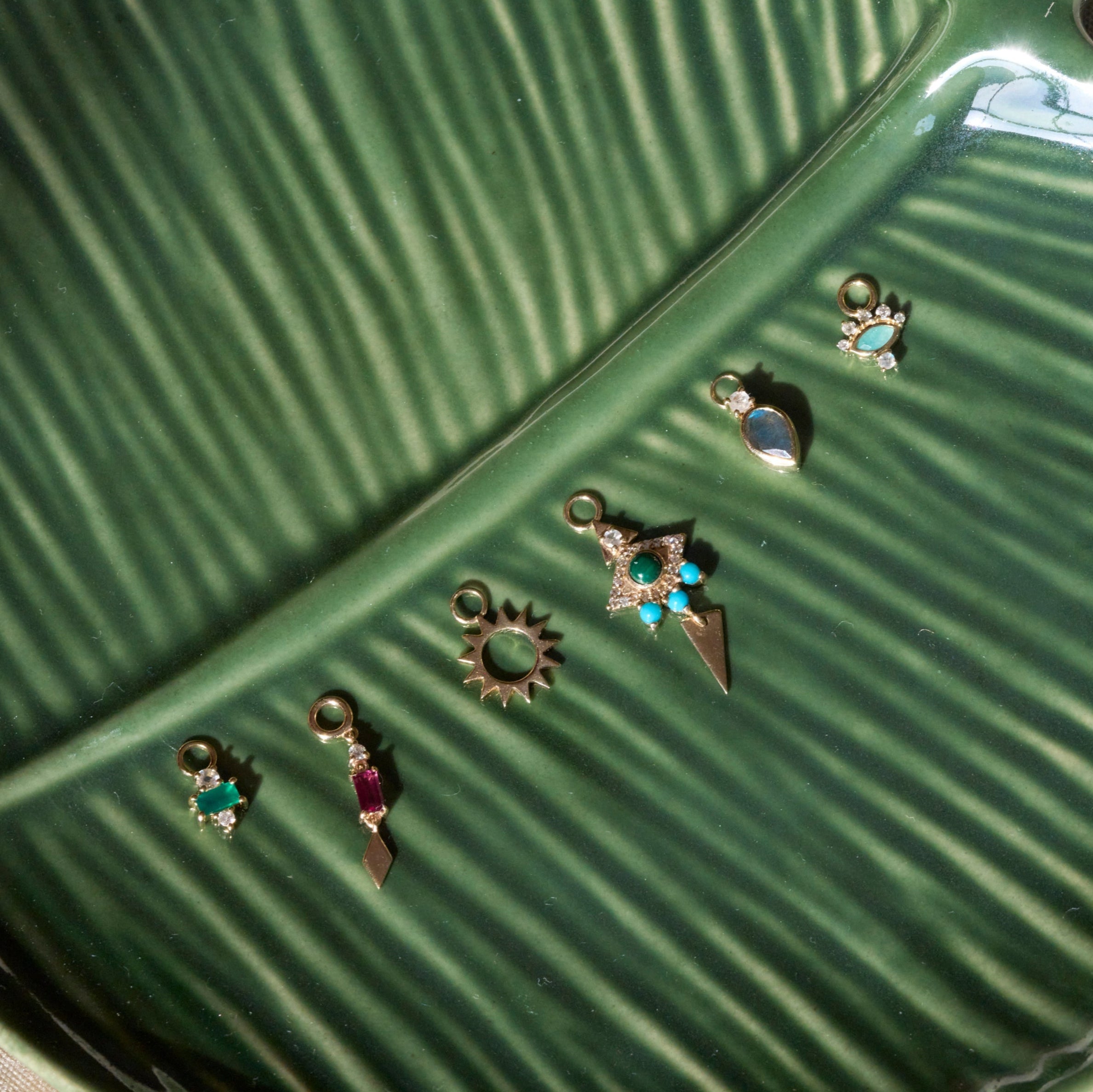 solid gold earring charms displayed on leaf porcelain dish including the Amazonite, Diamond & Moonstone Eye Earring Charm 9k Gold