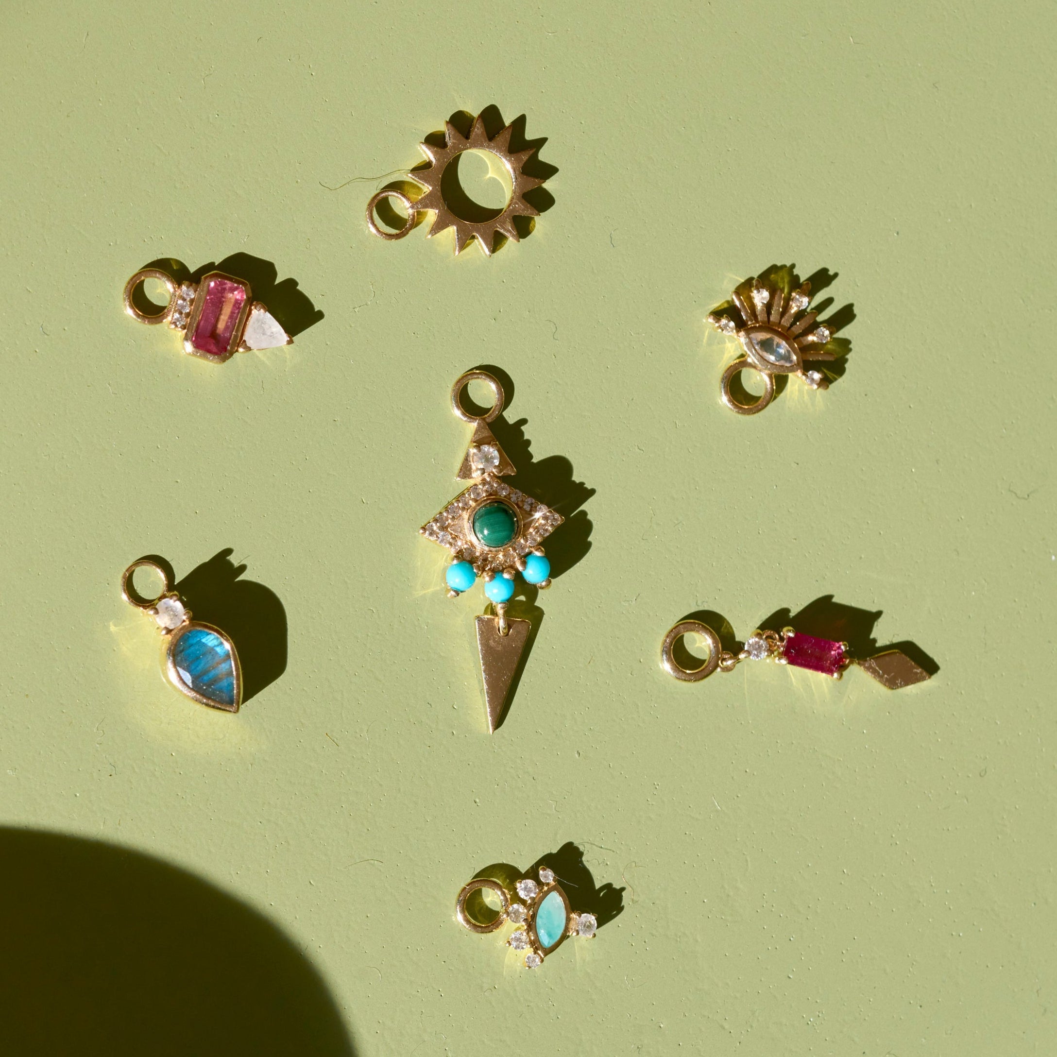 solid gold earring charms displayed on hard surface including the Amazonite, Diamond & Moonstone Eye Earring Charm 9k Gold