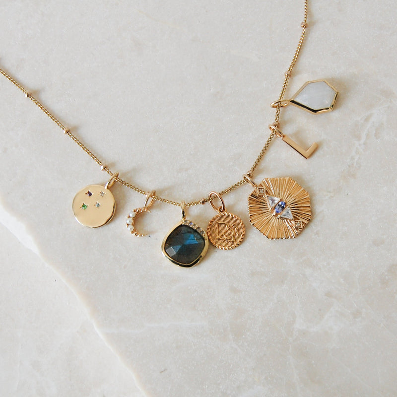 solid gold pendant collection on marble surface including the Grecian Labradorite Stone Pendant 9k Gold