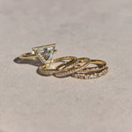 Three gold rings with diamond accents on a light pink surface