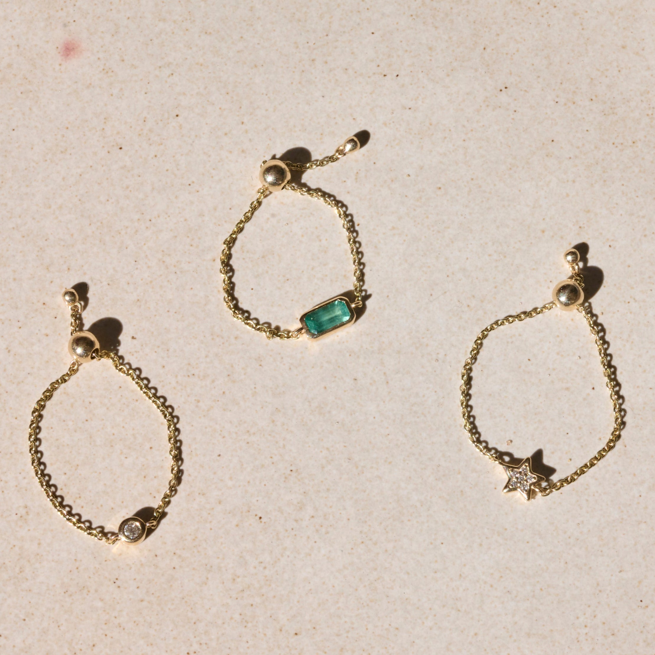solid gold chain rings on hard surface including the Diamond Star Chain Ring 9k Gold