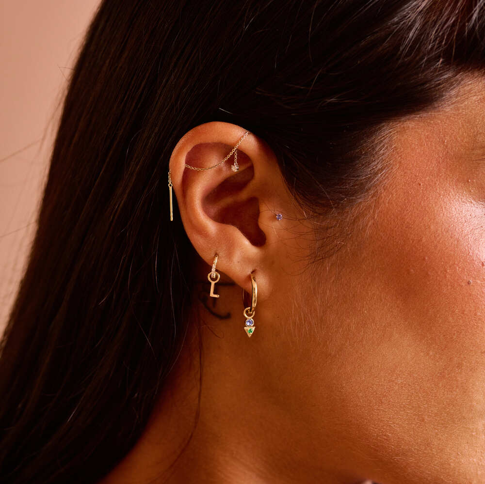model wearing ear stack including the initial charm in solid gold