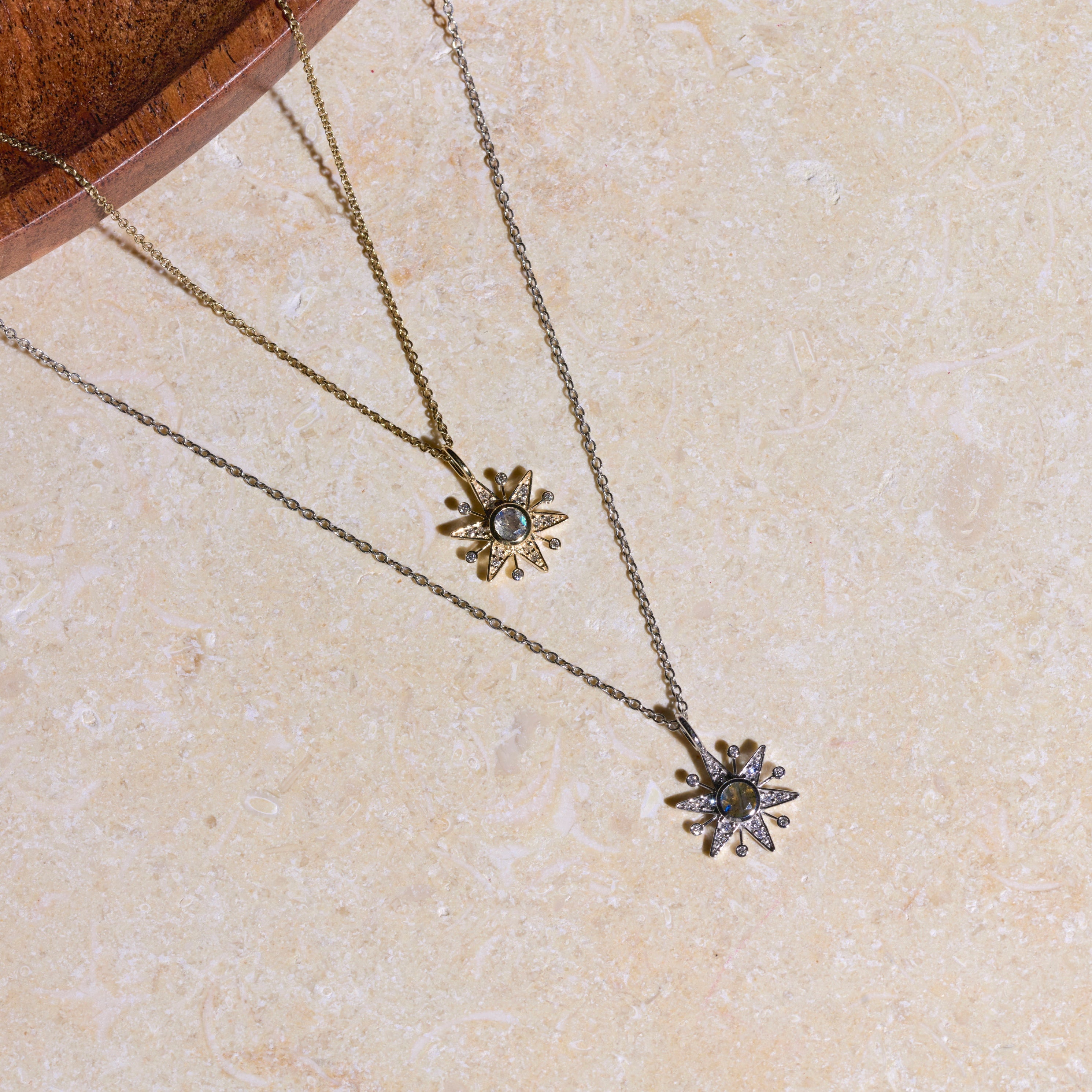 Two necklaces with floral pendants on a beige surface