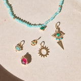 solid gold pendants on hard surface including the Limited Edition Malachite Eye Pendant 9k Gold