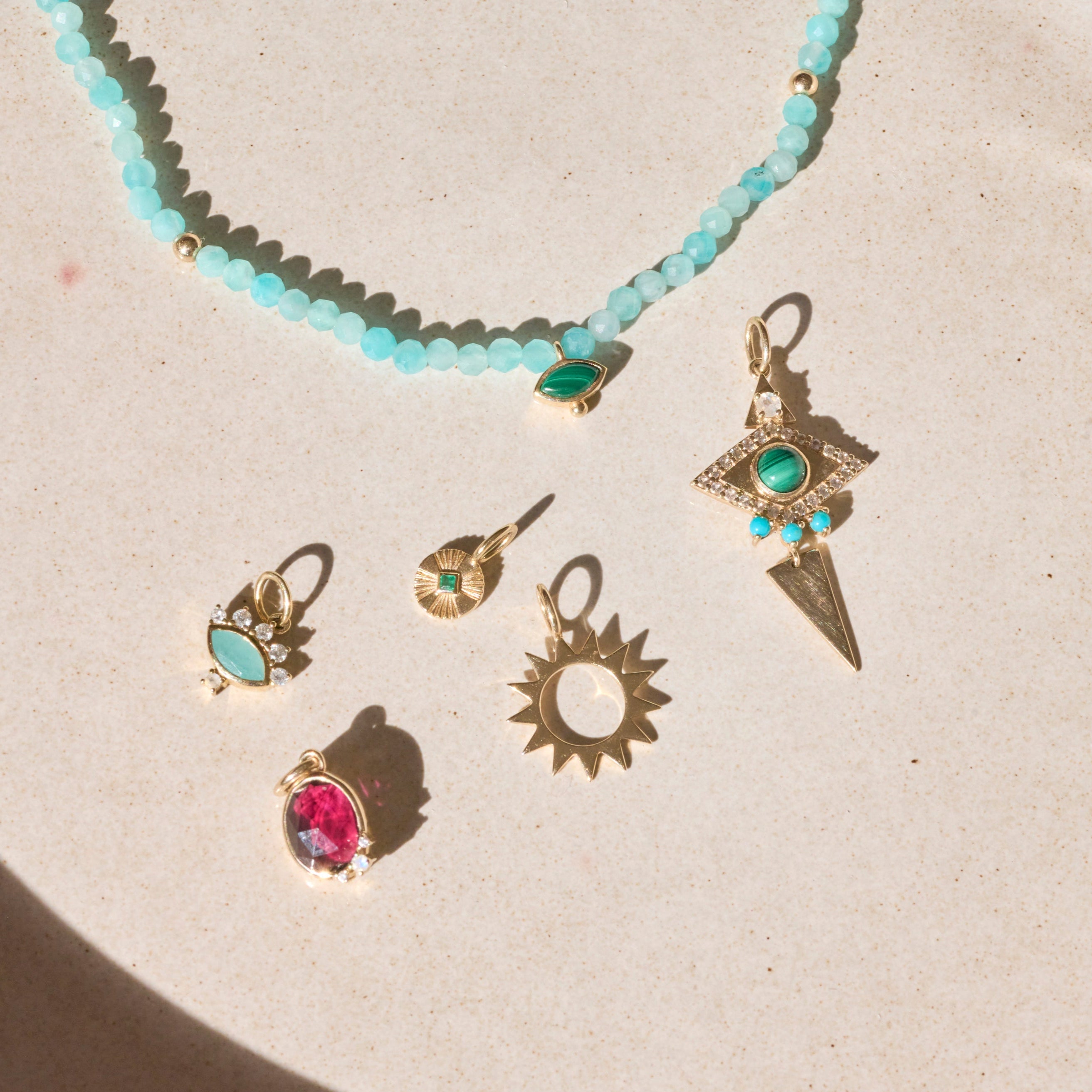 solid gold pendants on hard surface including the Limited Edition Malachite Eye Pendant 9k Gold