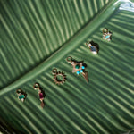 solid gold earring charms displayed on leaf dish including the Limited Edition Malachite Eye Hoop Earrings 9k Gold