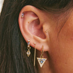 Close-up of a person wearing multiple earrings with a blurred background