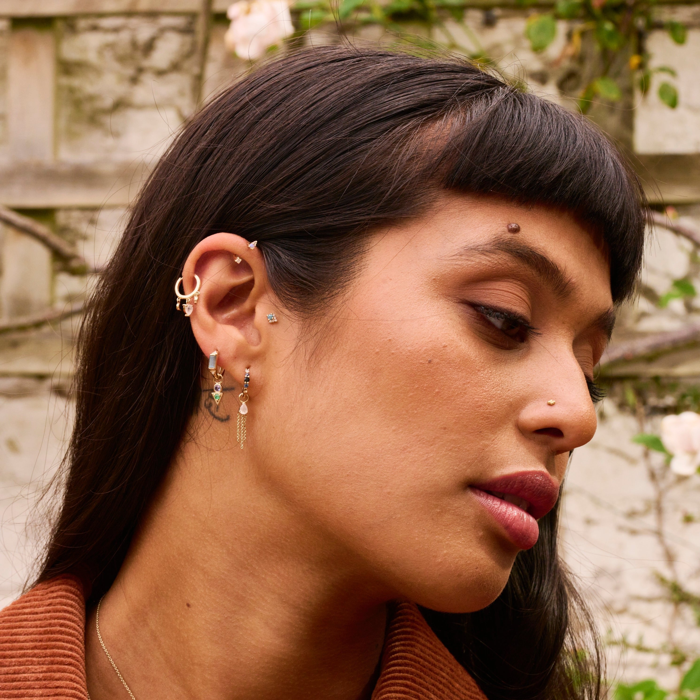 model wearing solid gold earrings including the London Blue Topaz & Diamond Arrow Flat Back 9k Gold