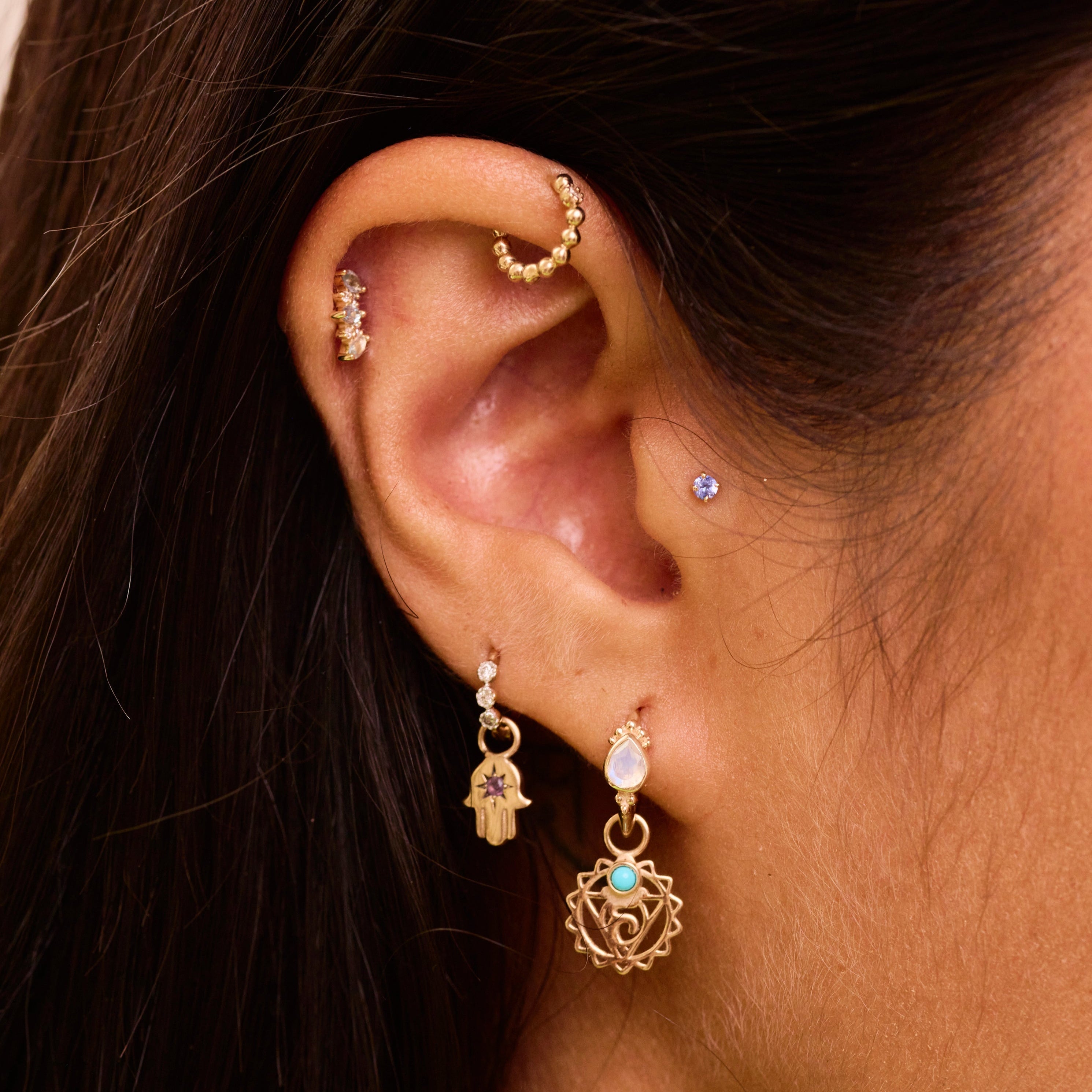 solid gold ear stack close up showing earrings including the Mini Diamond Beaded Huggie Hoop 9k Gold in upper helix