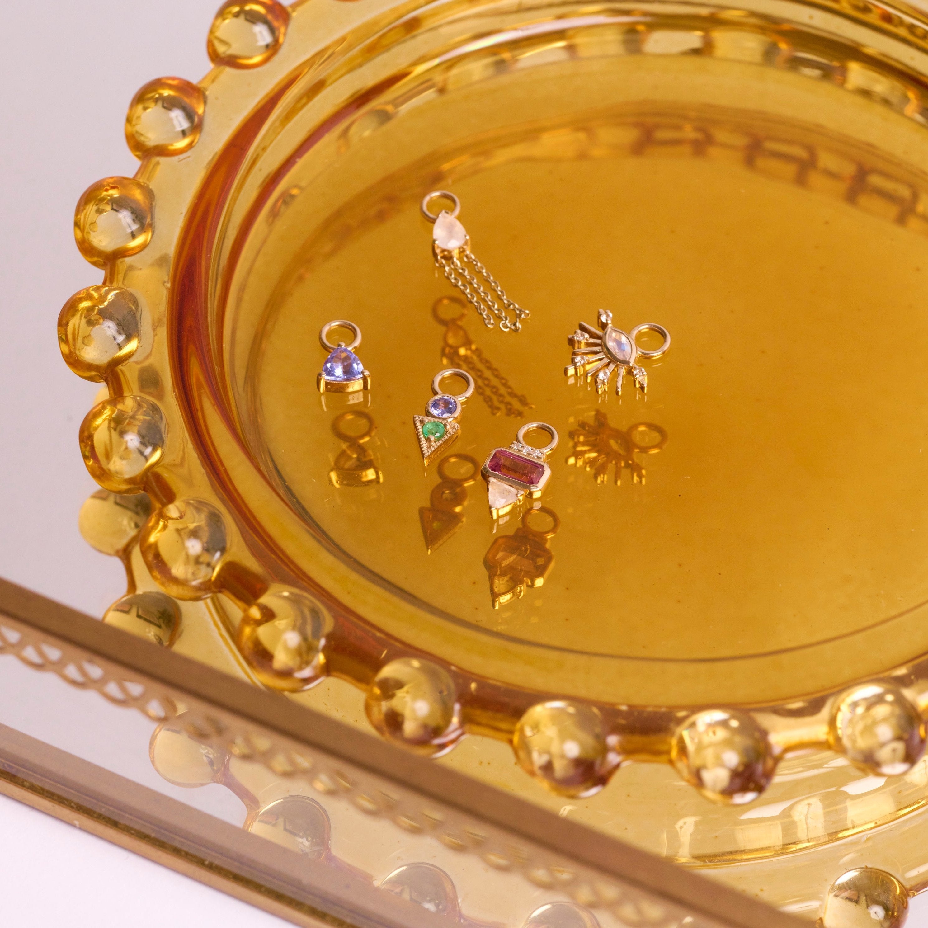 solid gold earring charms in glass dish including the Pink Tourmaline, Diamond & Moonstone Earring Charm 9k Gold