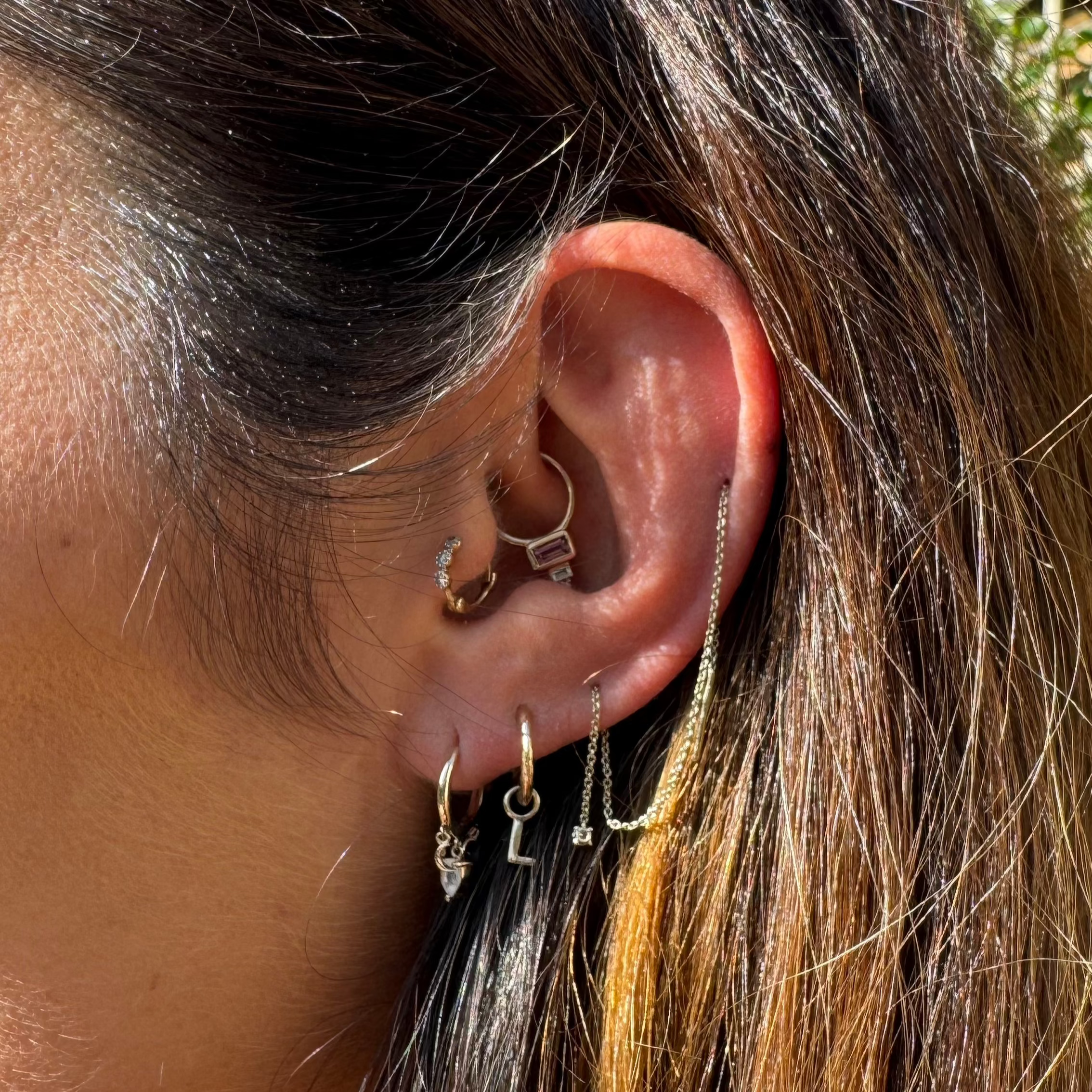 ear stack close up showing solid gold earrings including the Pink Tourmaline, Diamond & Topaz Daith Hoop 9k Gold