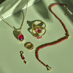 solid gold rhodolite garnet pieces displayed on green tray including the Rhodolite Garnet, Moonstone & White Sapphire Necklace 9k Gold