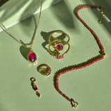 solid gold rhodolite garnet pieces displayed on green tray including the Rhodolite Garnet, Moonstone & White Sapphire Necklace 9k Gold