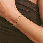 Solid Gold bangle on model wearing brown dress