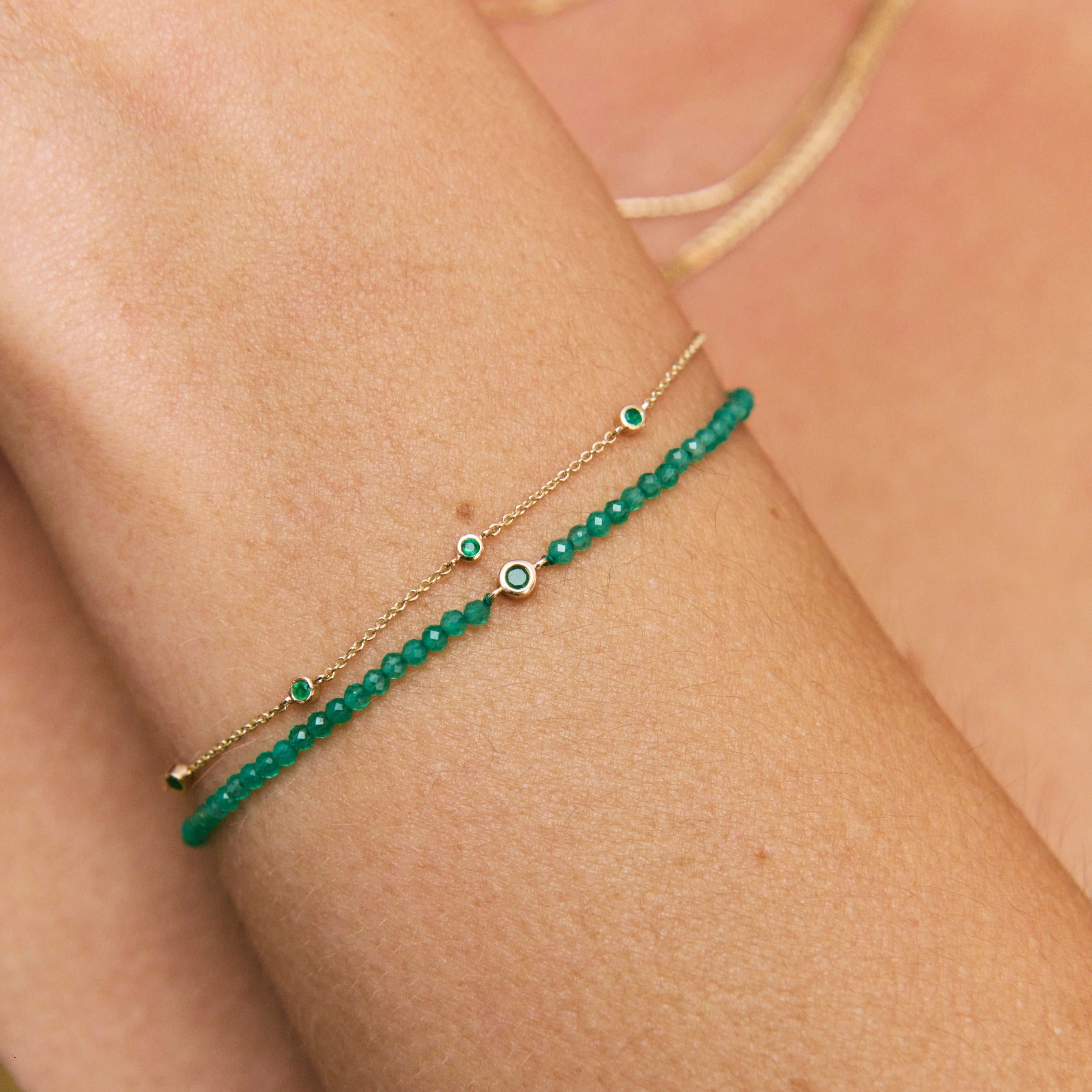 Green beaded bracelet on a wrist with a neutral background