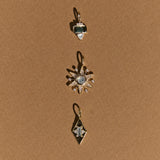 Three gold pendants with gemstones on a brown background