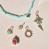 solid gold pendants displayed on hard surface including the Sunburst Silhouette Pendant 9k Gold