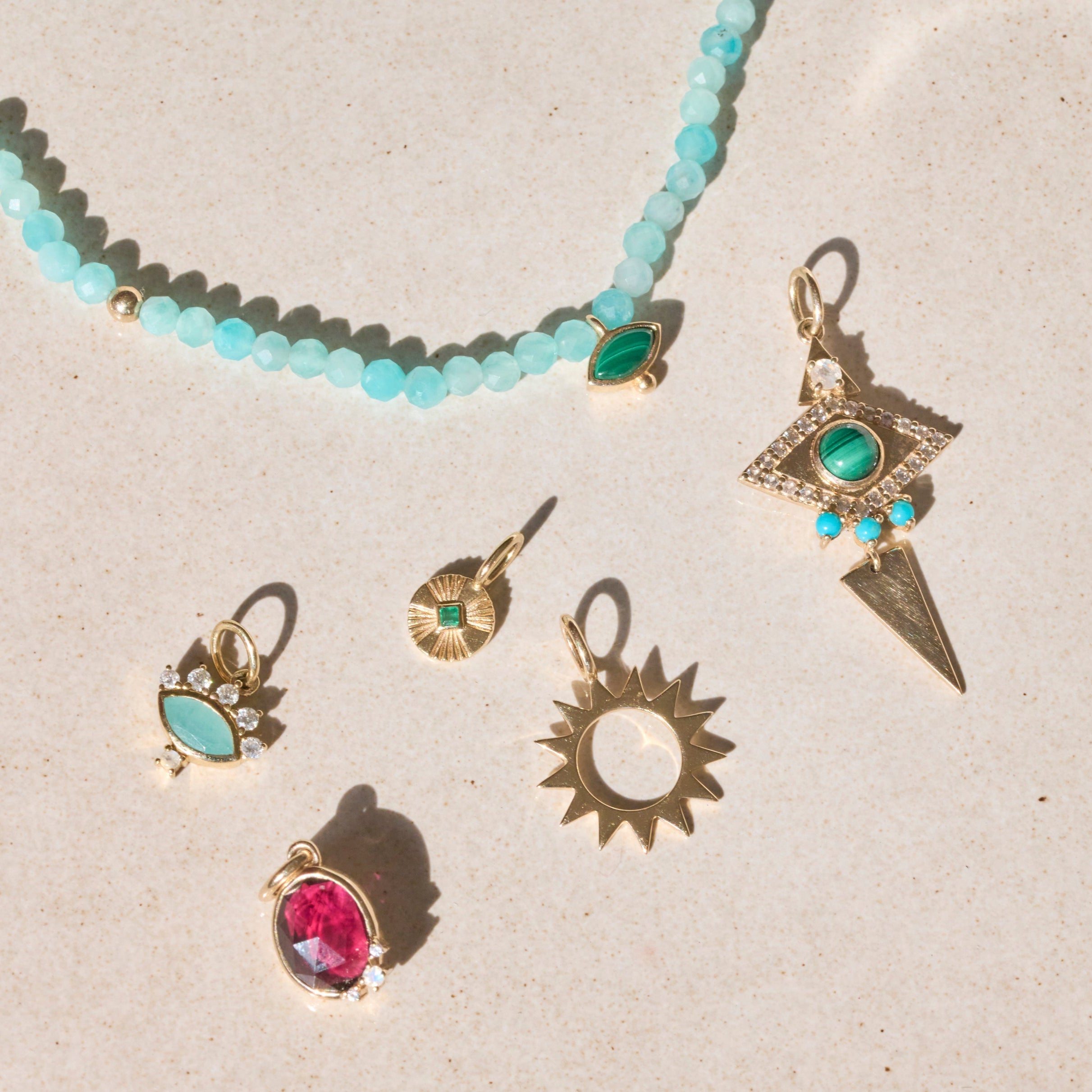 solid gold pendants displayed on hard surface including the Sunburst Silhouette Pendant 9k Gold