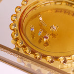 solid gold earring charms in glass dish including the Tanzanite & Emerald Geo Earring Charm 9k Gold