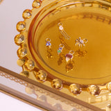 solid gold earring charms in glass dish including the Tanzanite & Emerald Geo Earring Charm 9k Gold