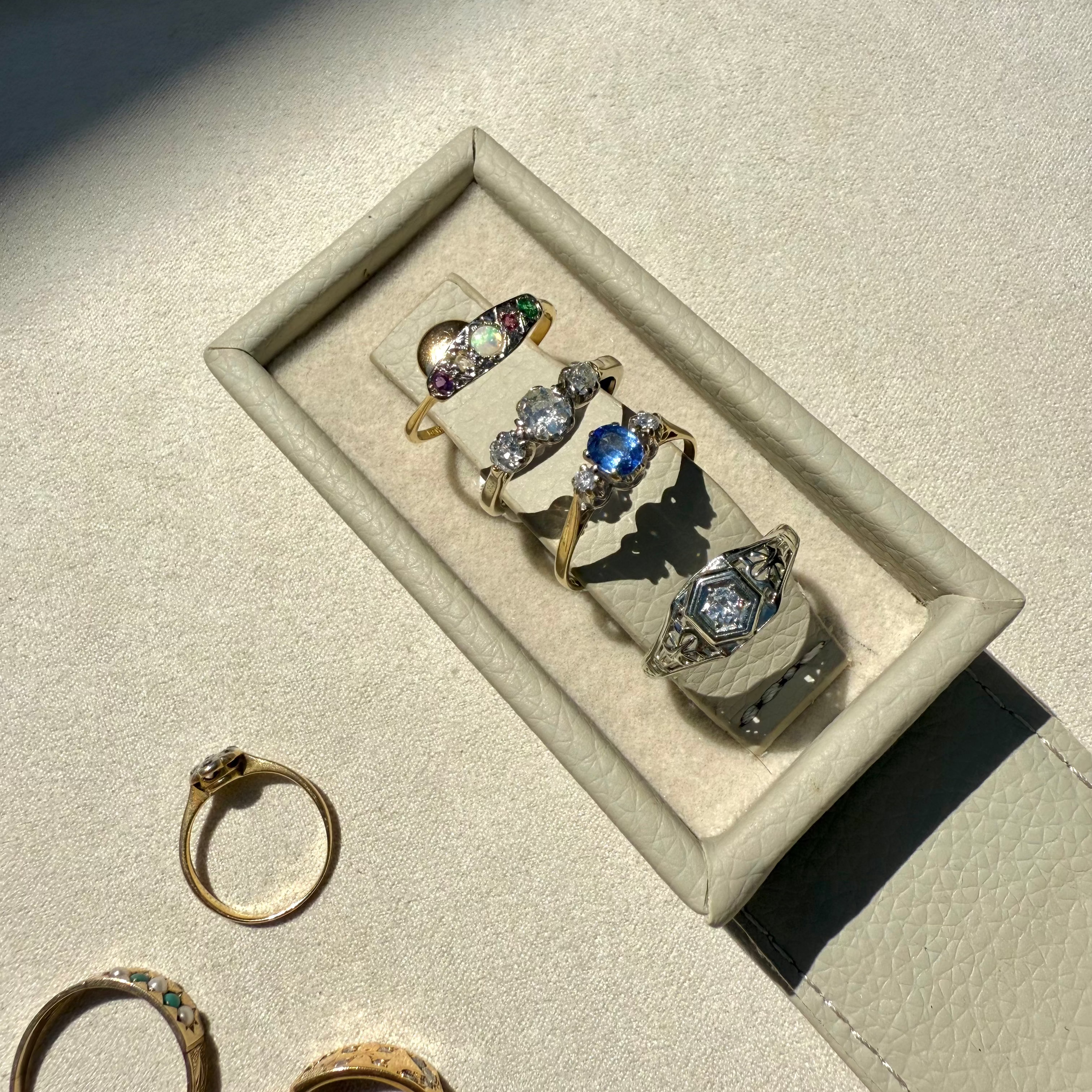 Set of rings displayed on a light gray surface with a jewelry box.