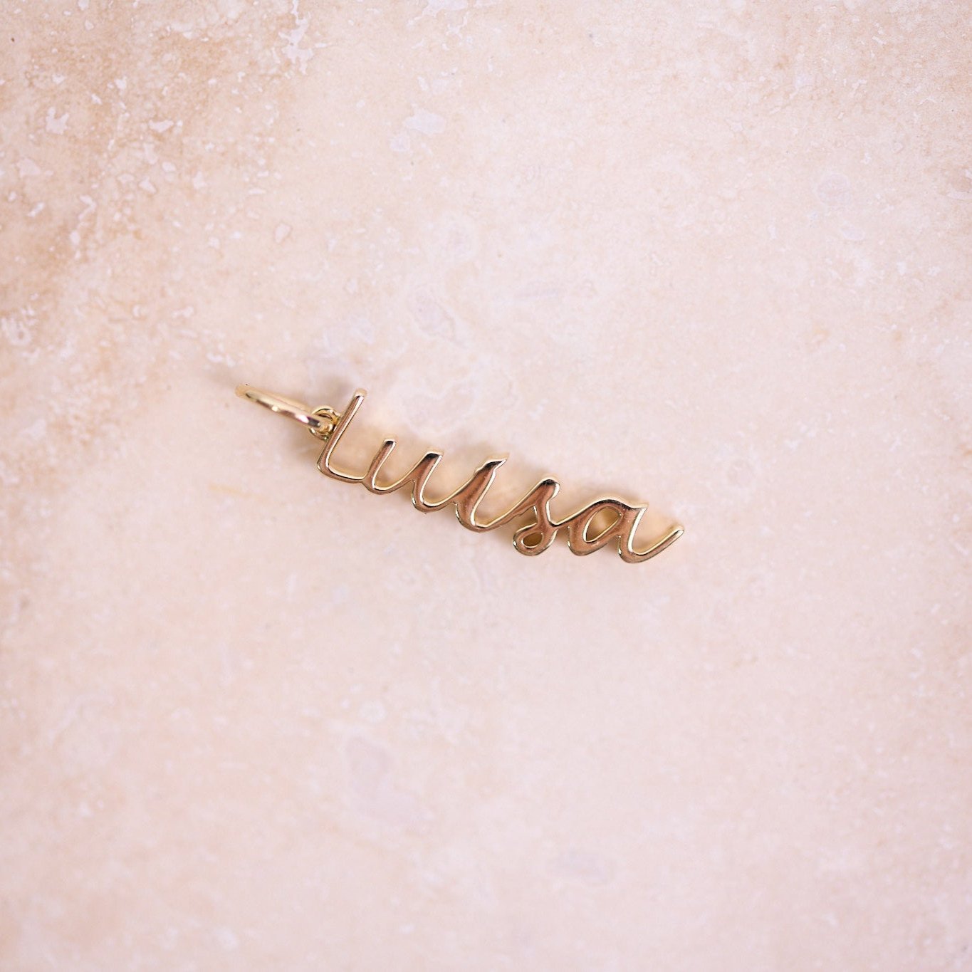 Name Pendant 9k Gold on hard surface