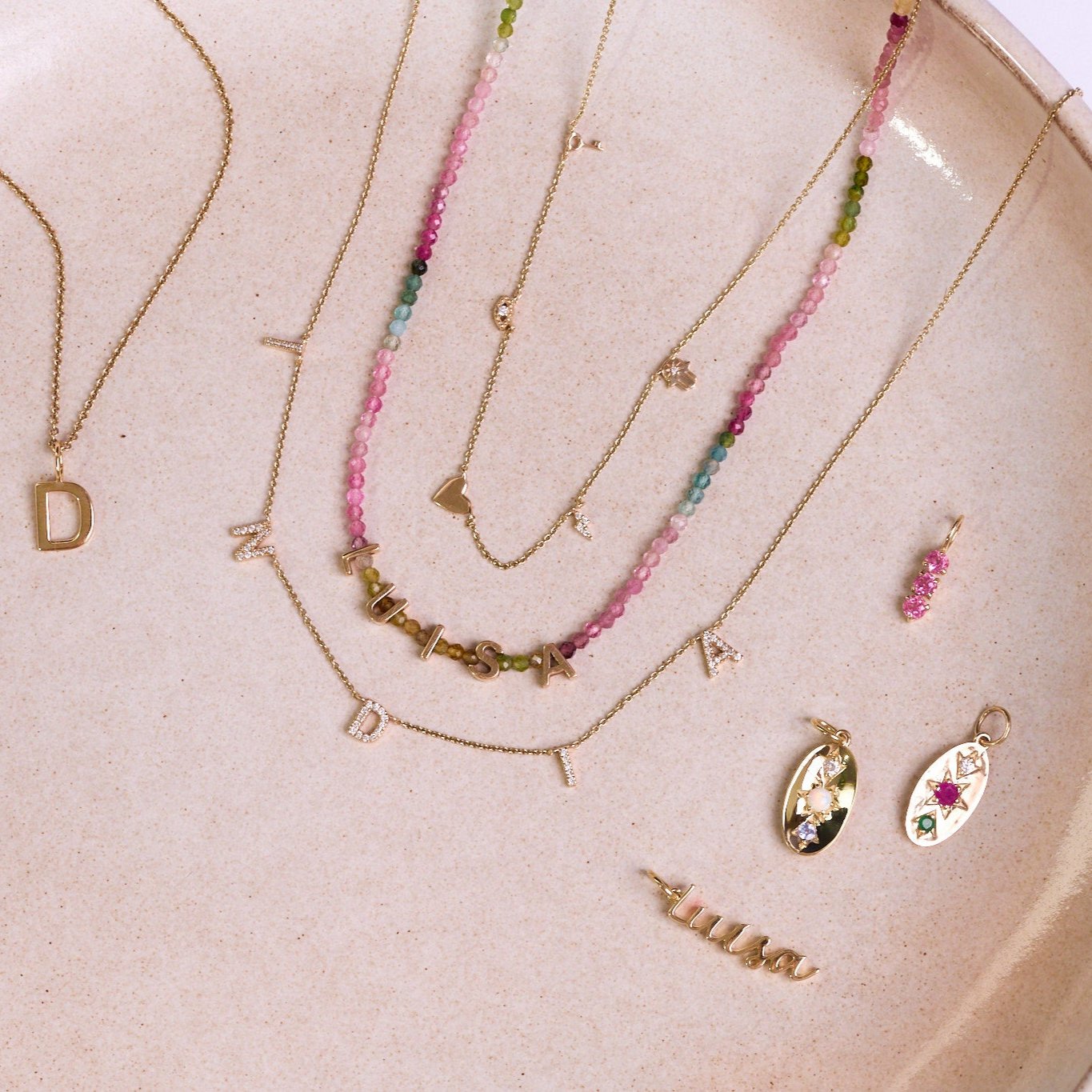 Solid 9k gold pieces on a porcelain plate including the Personalised Diamond Initial Necklace 9k Gold