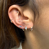 Close-up of an ear with multiple gold earrings featuring gemstones.