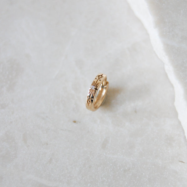 Diamond Starburst Huggie Hoop Earring 9k Gold on marble surface
