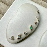 Set of earrings on a white cushion with a beige fabric background