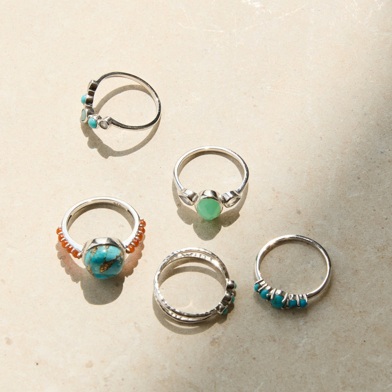 sterling silver rings on hard surface including the Copper Turquoise & Orange Carnelian Ring Sterling Silver