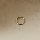 Hammered Huggie Hoop Earring 9k Gold on hard surface