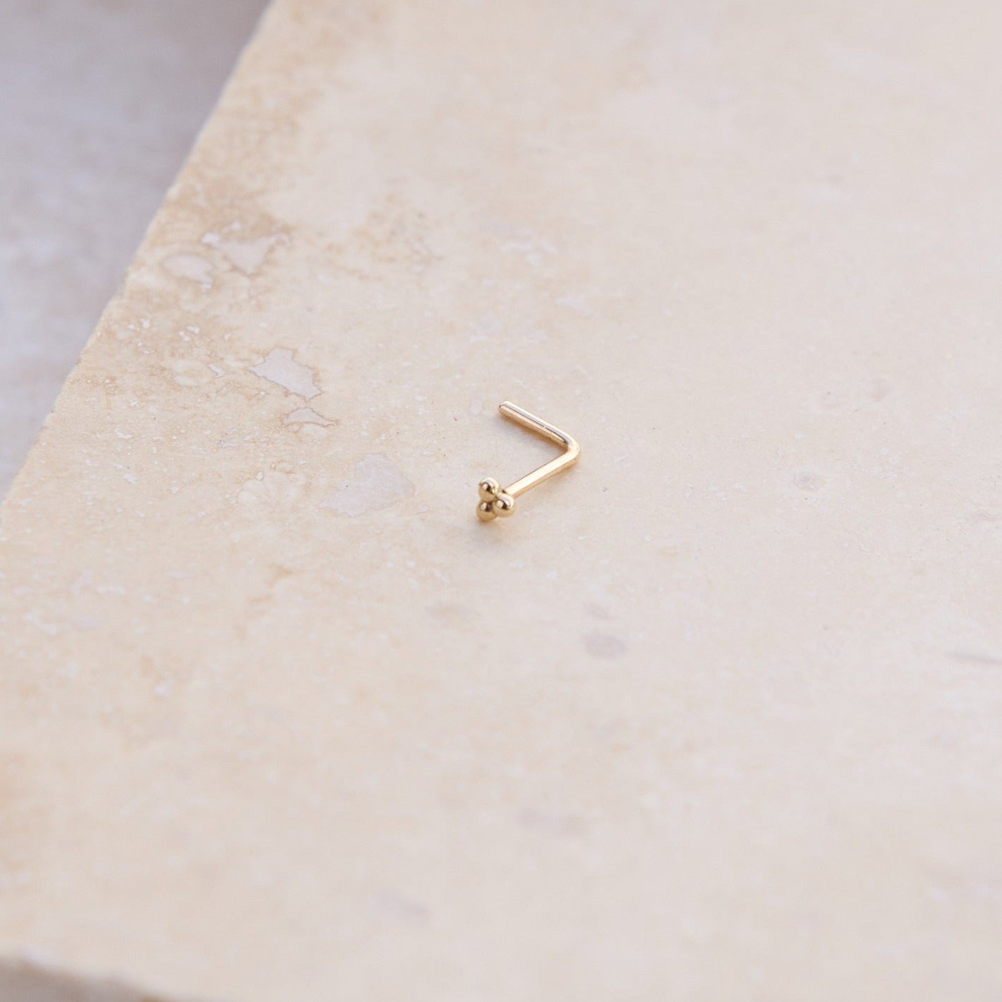 Trilogy Nose Stud 9k Gold on hard surface