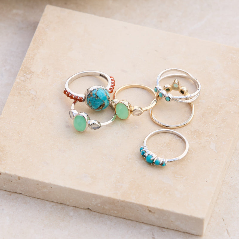 gold and silver rings on a piece of stone including the Chrysoprase & Moonstone Ring 9k Gold
