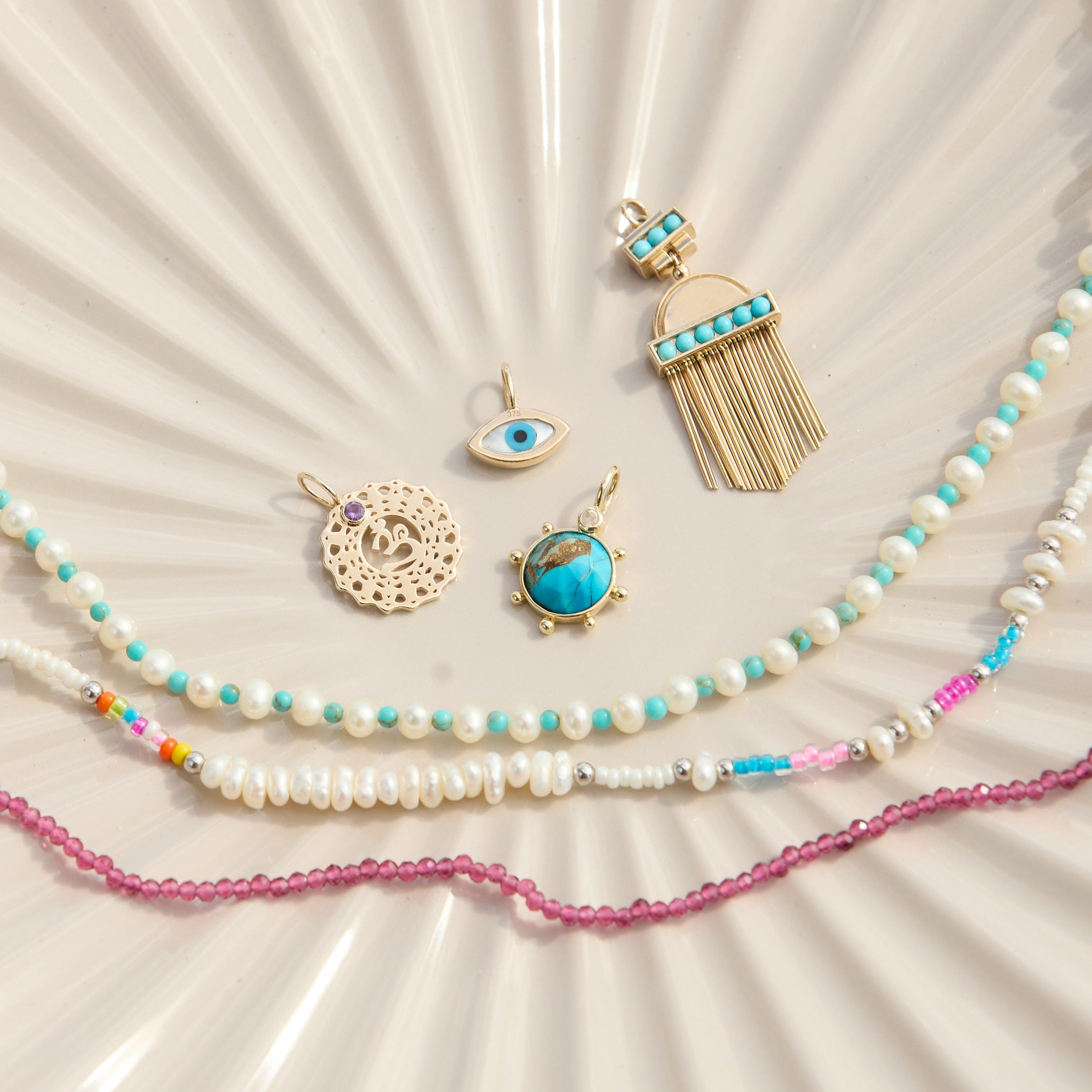 solid gold pendants and beaded pieces on porcelain dish including the Aztec Turquoise Pendant 9k Gold