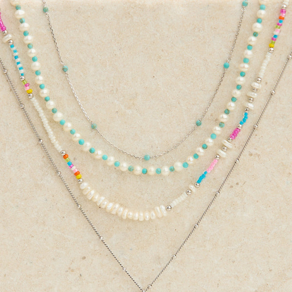 sterling silver and beaded necklaces layered on stone surface including the Pearl & Turquoise Necklace Sterling Silver