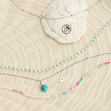 sterling silver jewellery pieces displayed on textured  surface including the Pearl & Turquoise Necklace Sterling Silver