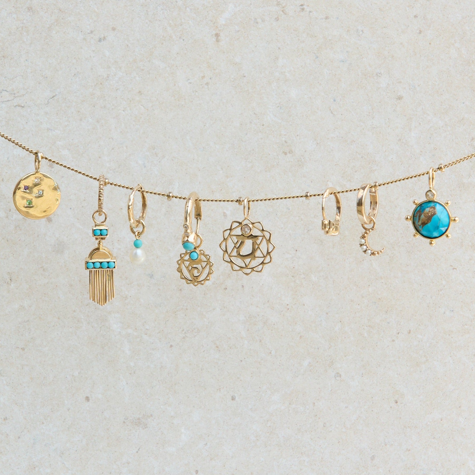 solid gold pendants and earrings hanging from stationed bead chain including the Copper Turquoise & Moonstone Pendant 9k Gold 