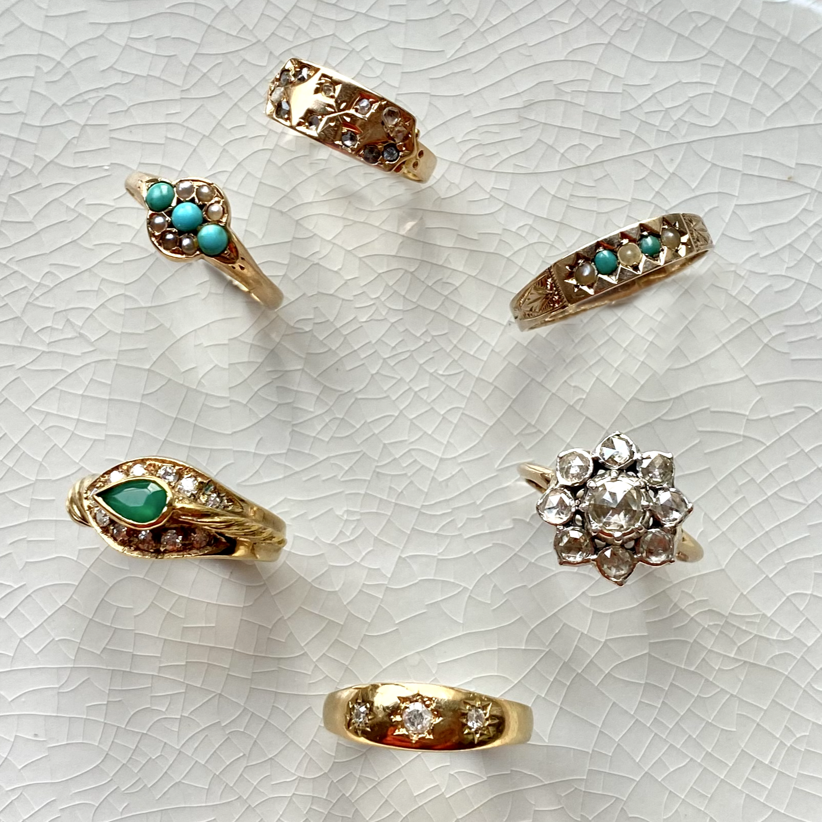 solid gold vintage rings displayed on a tile including the 15kt Gold Diamond Floral Cluster Vintage Ring