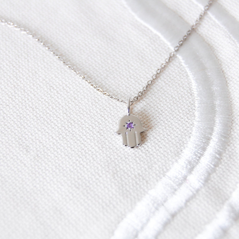 amethyst silver hand of fatima necklace on white fabric