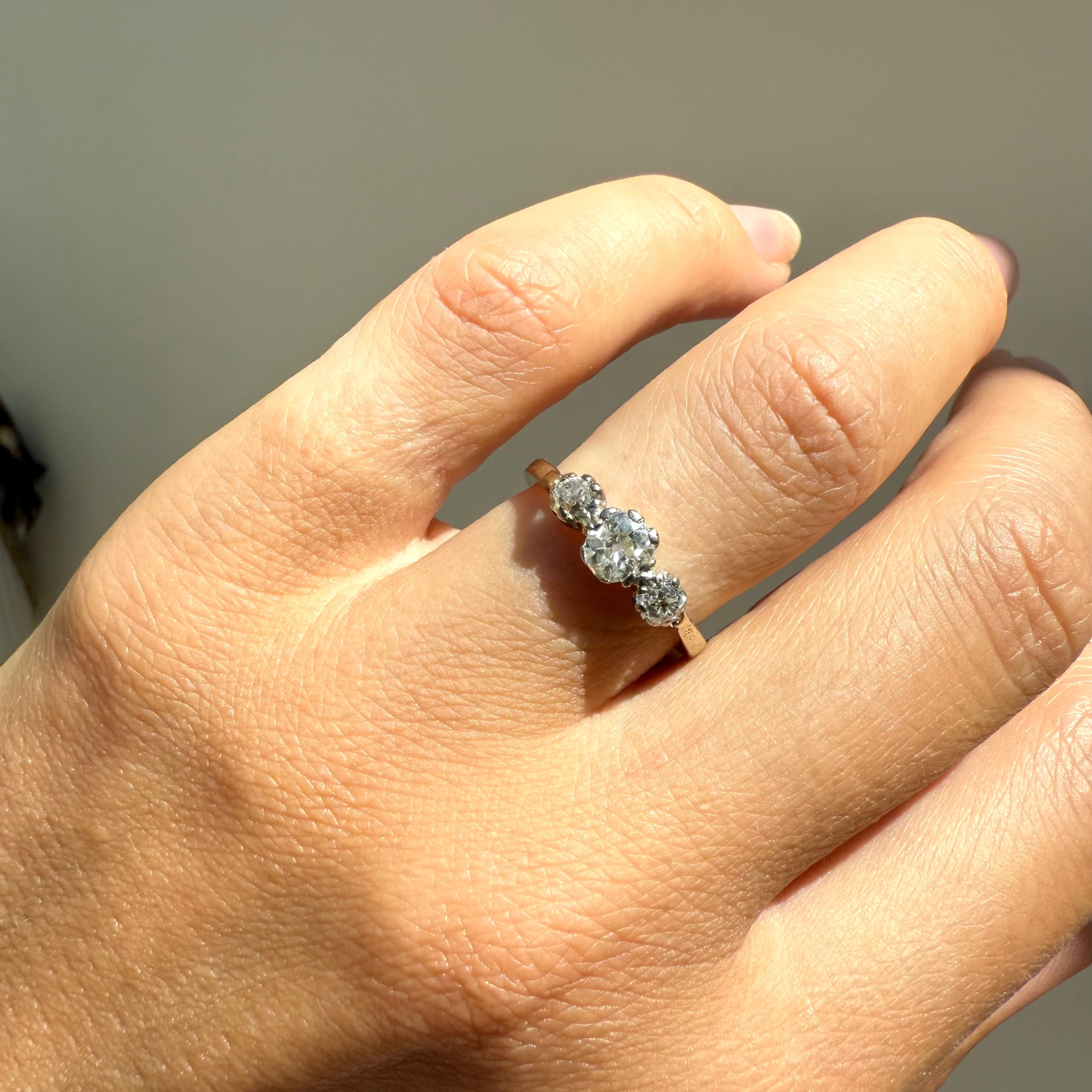Close-up of a hand wearing a diamond ring on a neutral background