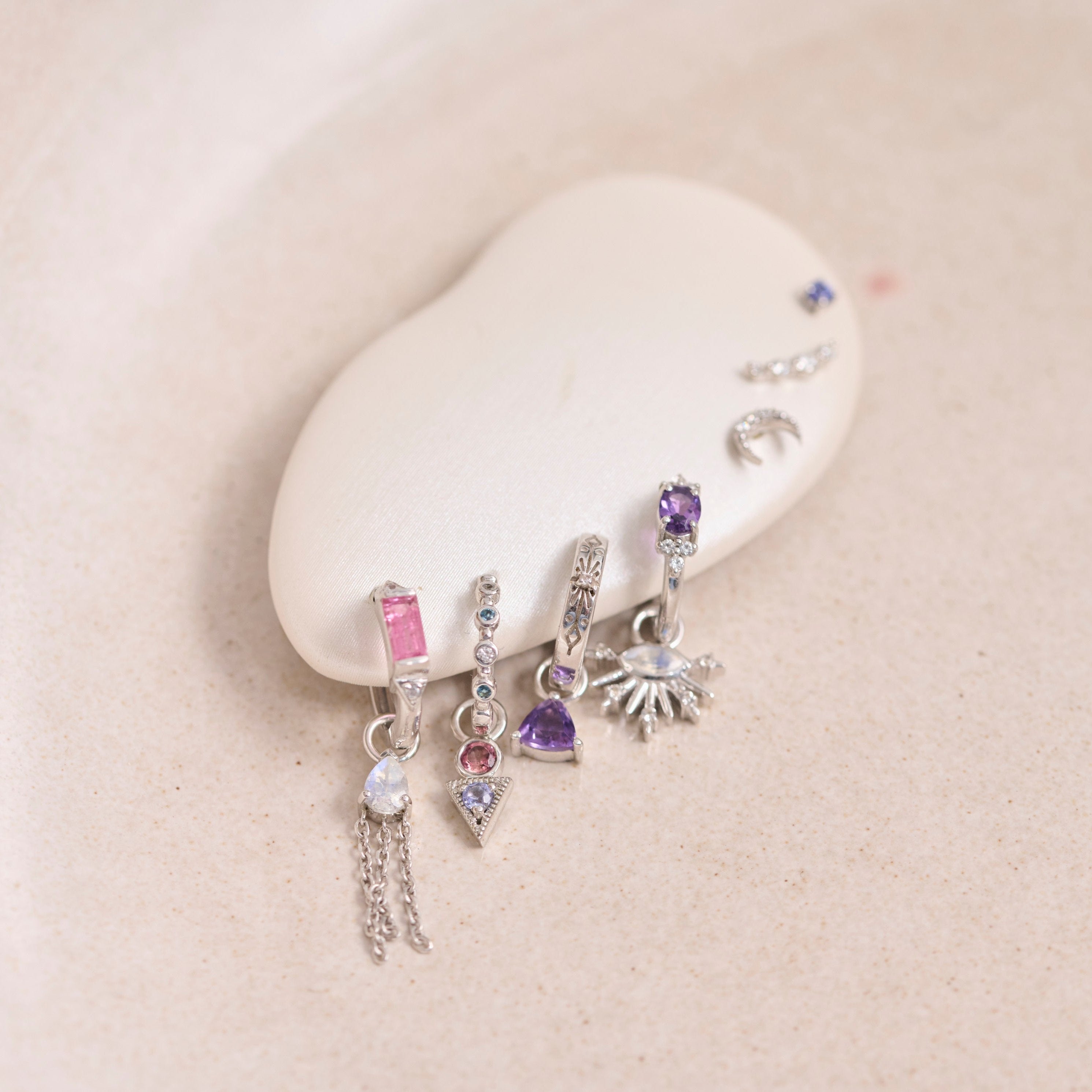 ear display showing sterling silver huggies and charms including the Amethyst Trillion Earring Charm Sterling Silver
