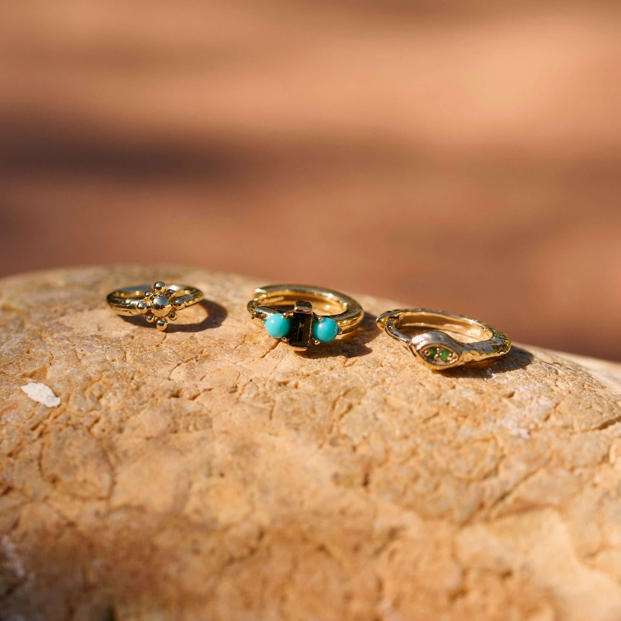 Beaded Flower Seamless Huggie Earring 9k Gold on a rock displayed with other solid gold huggies