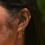 model wearing the Beaded Flower Seamless Huggie Earring 9k Gold along with other solid gold earrings