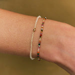 Two bracelets on a wrist against a neutral background