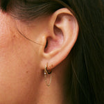 Close-up of an ear wearing a gold hoop earring with a blurred background