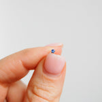 model hand holding the Mini Tanzanite Solitaire Flat Back Earring 14k White Gold