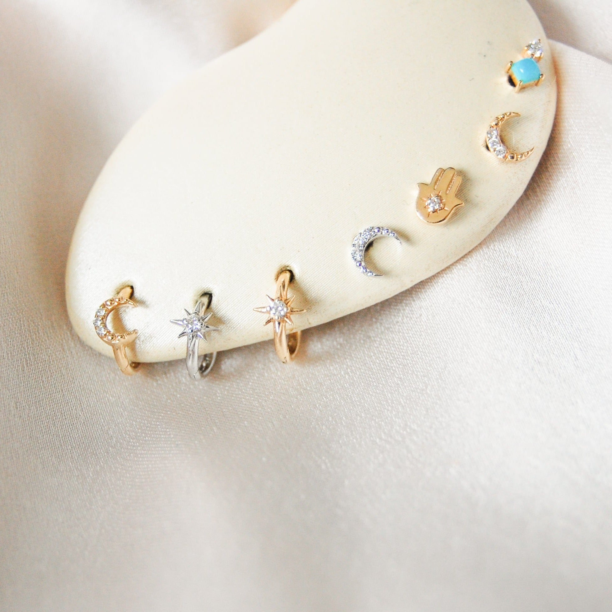 earring stack on ear cushion including the Diamond North Star Seamless Huggie Hoop Earring 9k Gold