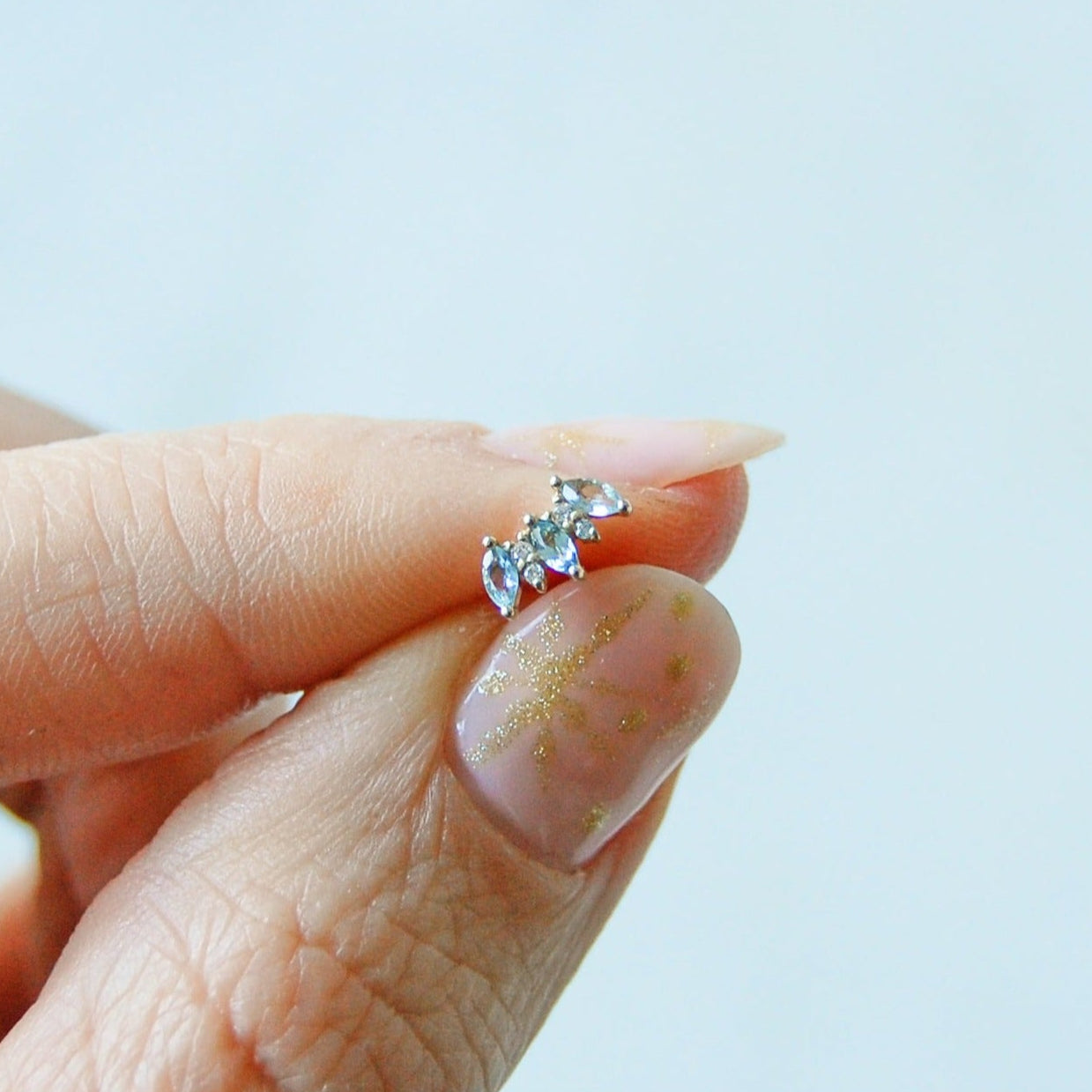 model hand holding the aquamarine & diamond flat back earring 14k gold